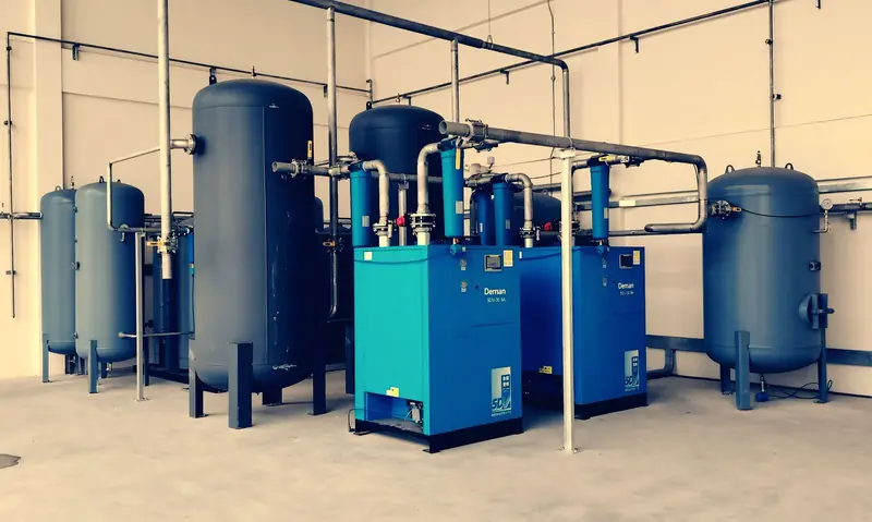Industrial air compressor setup with blue tanks and pipes inside a plant