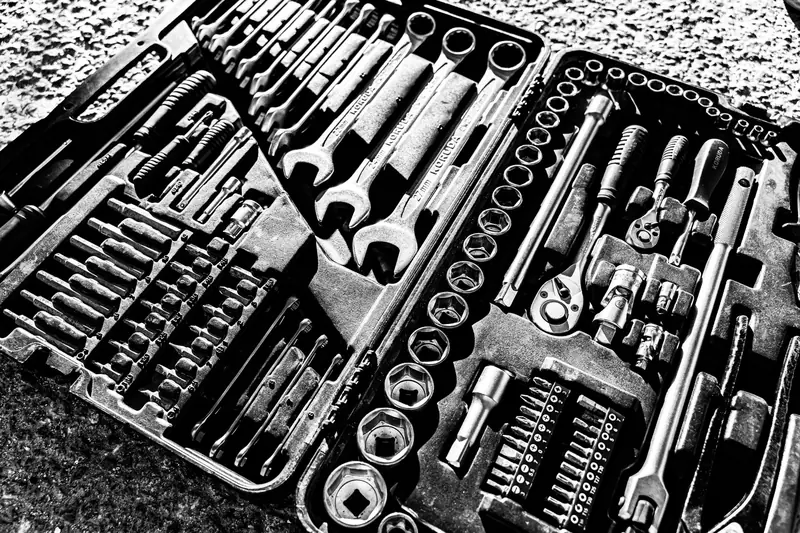 Close-up black and white photo of a complete wrench and socket tool set within a toolbox
