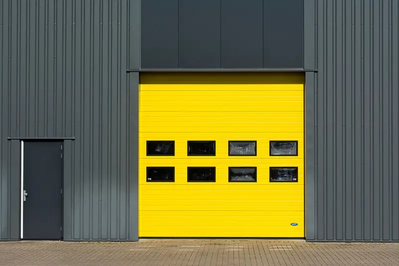 A sleek industrial structure featuring a vibrant yellow garage door for architectural interest