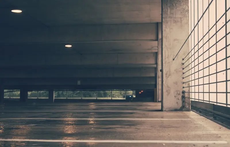 Deserted indoor parking garage with industrial design and wet concrete floor creating a moody ambiance