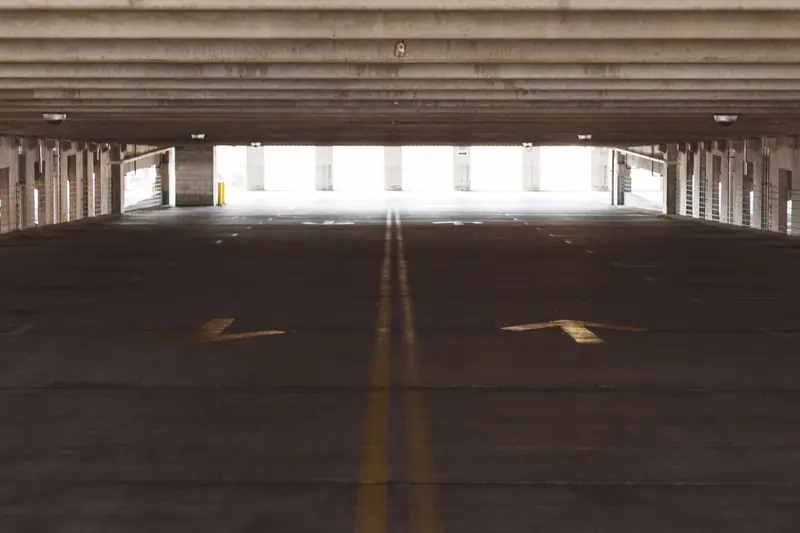 Spacious and empty parking garage interior with directional arrows on the floor, modern architecture