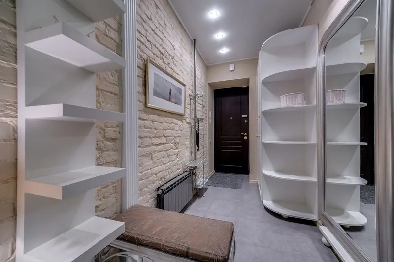 Contemporary entryway with sleek white shelving and neutral tones, featuring a comfortable bench