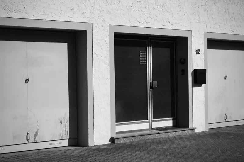 Monochrome photo of an urban building facade with garages and doors