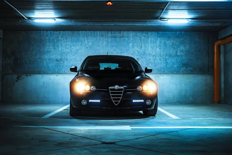 Front view of an Alfa Romeo parked in a modern underground garage, illuminated by cool lighting