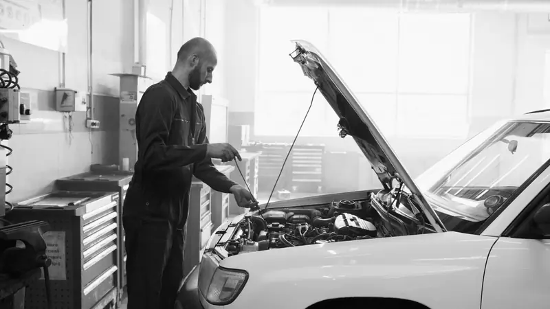 Mechanic in a garage performing engine maintenance on a vehicle