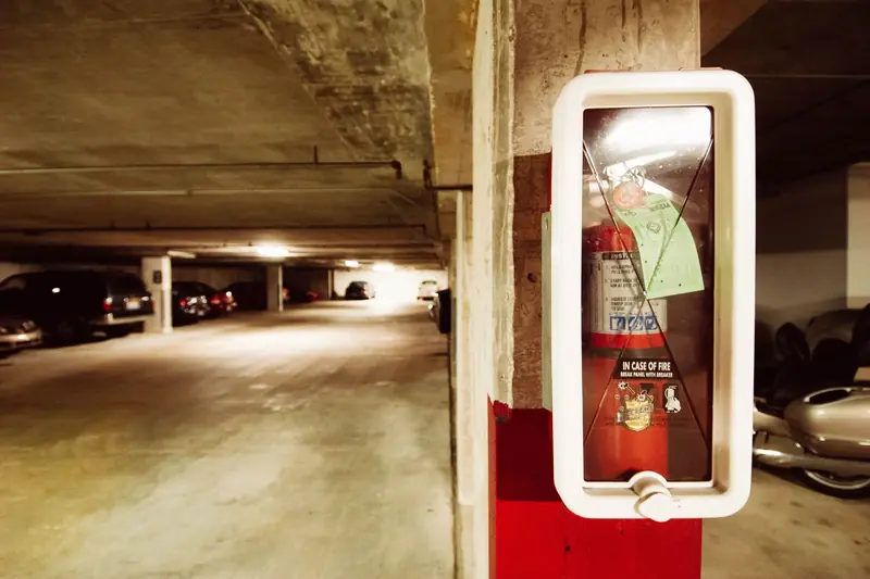 Fire extinguisher in an underground parking garage with parked cars