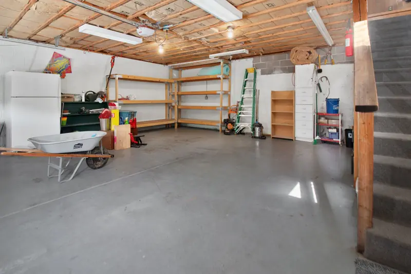 Spacious garage interior with storage shelves, tools, and a wheelbarrow, ideal for home organization