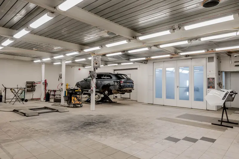 Interior view of a modern car repair garage with vehicle on lift and equipment