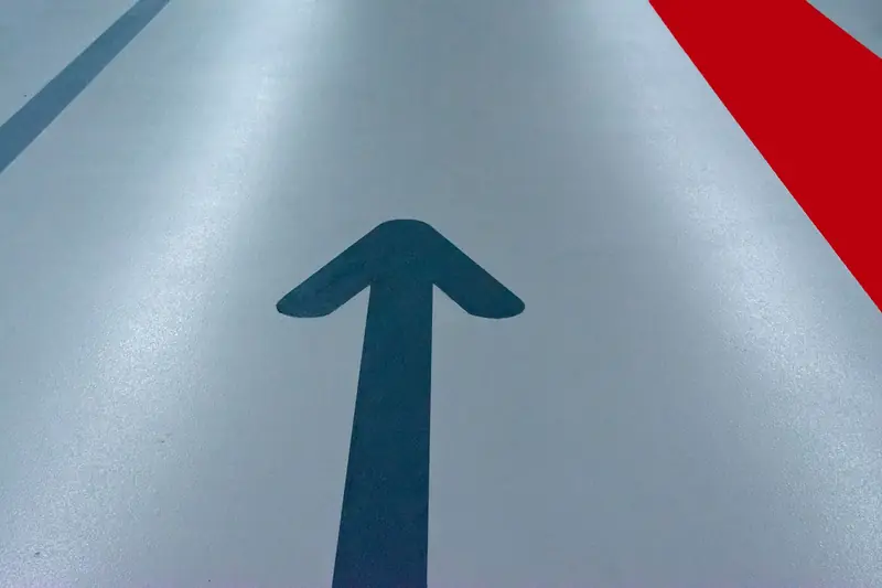 Blue arrow and red line on a parking garage floor signify direction and order