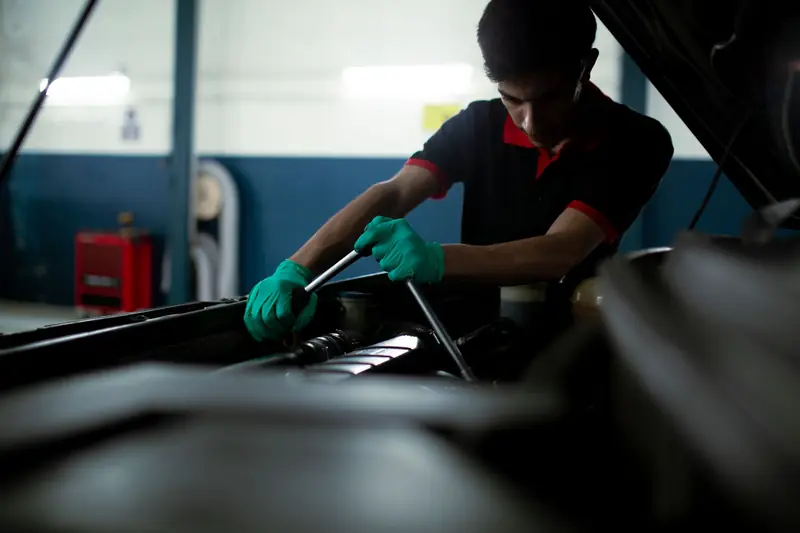 Mechanic wearing gloves using a torque wrench to repair a car engine in an indoor garage