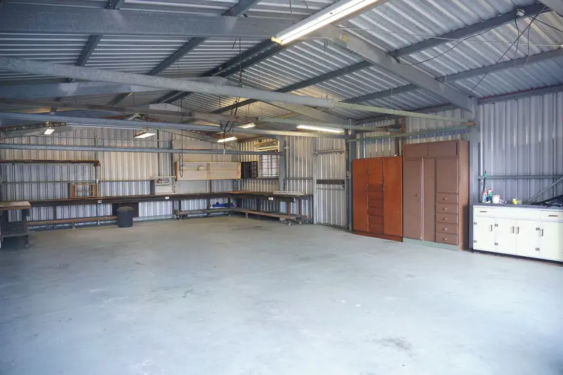 Empty industrial garage with steel walls and ceiling, featuring storage cabinets and workbenches