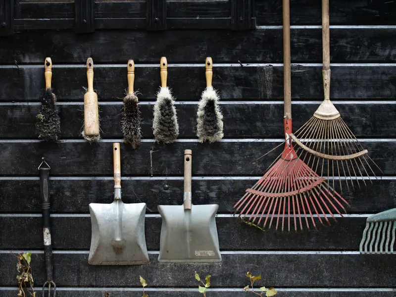 Neatly arranged garden tools hanging on a rustic wooden wall