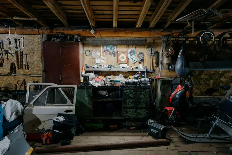 A cluttered garage interior with tools, motorcycle, and car door parts